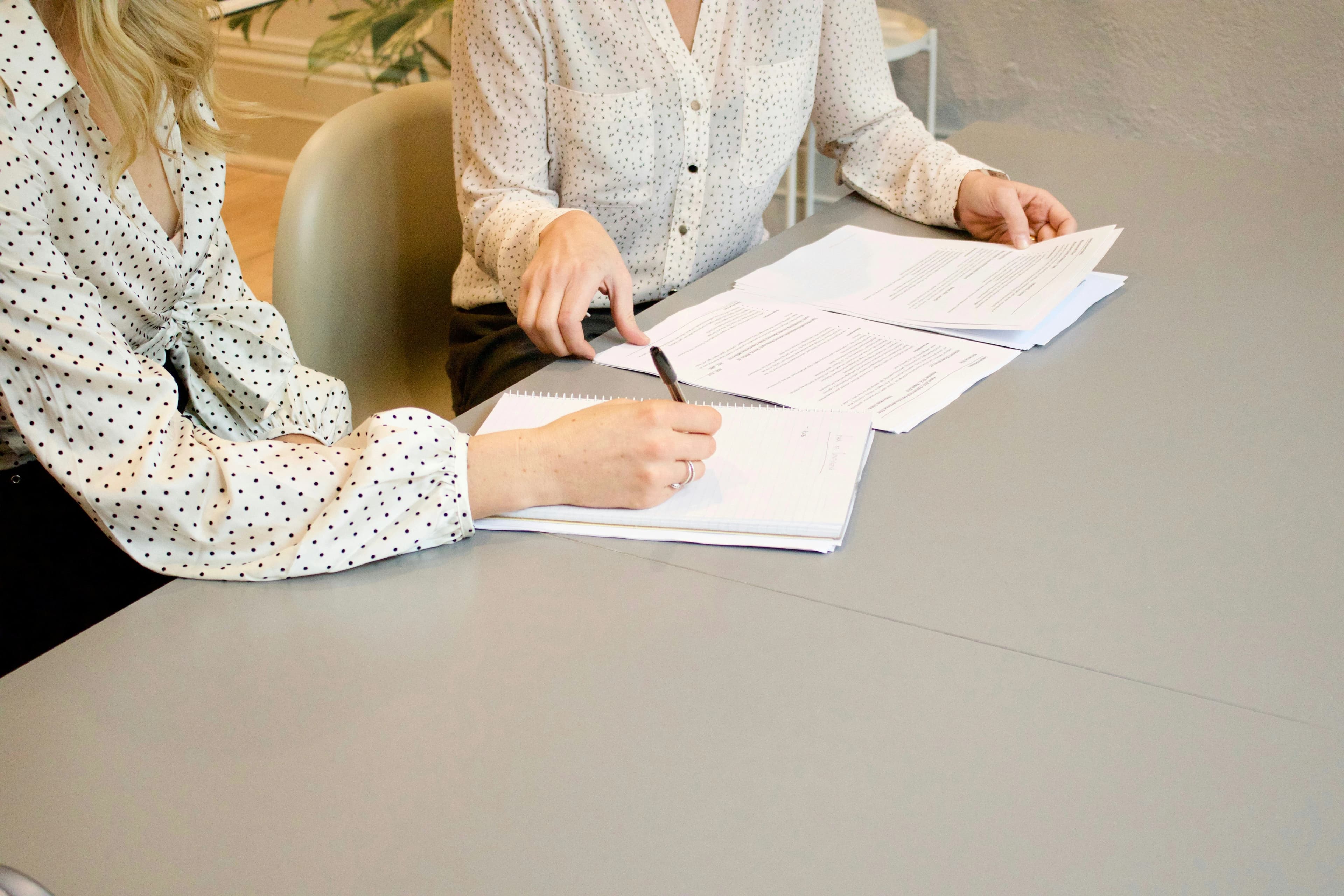 Two people reviewing and signing CV or job application documents